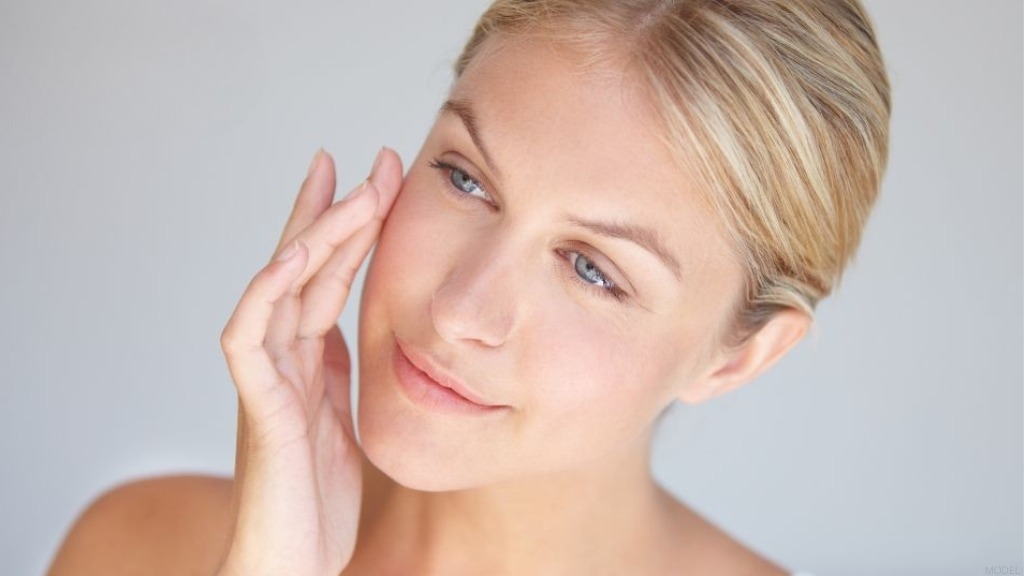 Woman is gently holding her hand to her face (model)