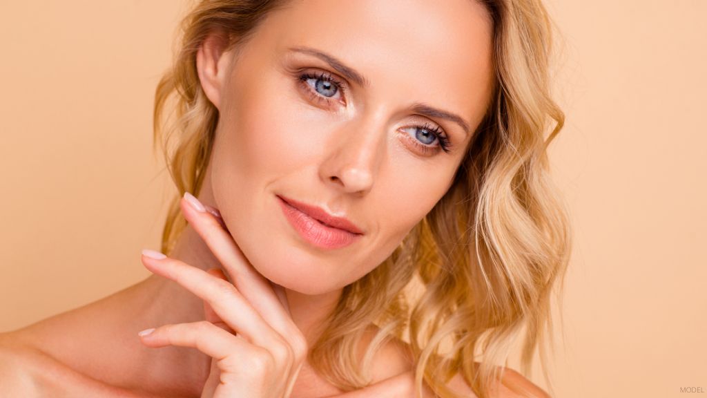 A woman posing with her hand on her chin. (Model)
