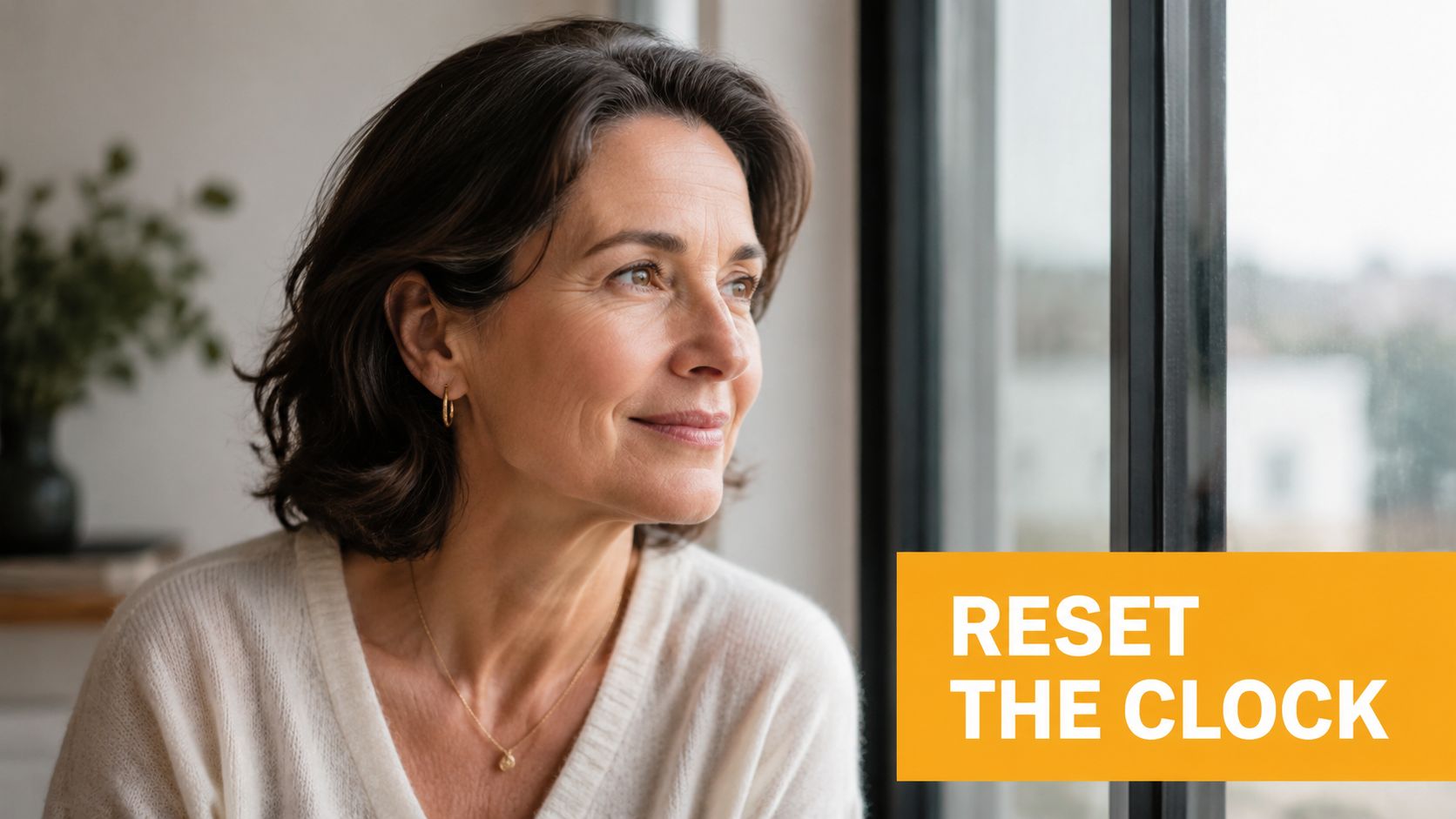 A middle-aged woman looking thoughtfully out of a window with the text overlay Reset the Clock.